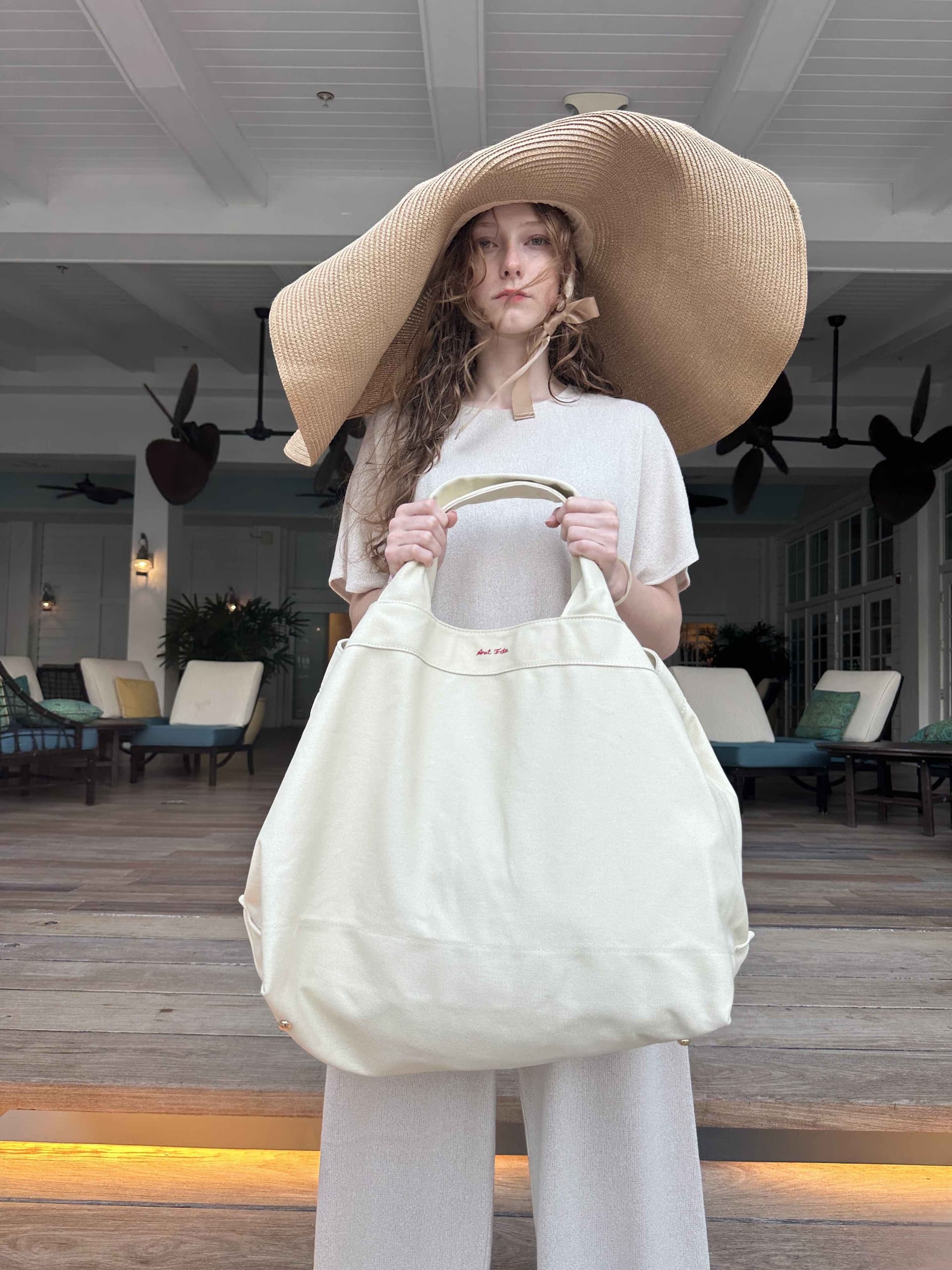Oversized canvas beach tote paired with luxury sun hat - summer carryall resort lifestyle